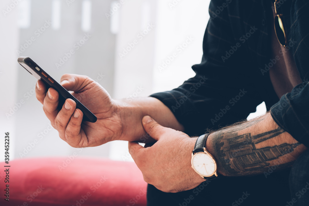 Aufkleber cropped view of man's hand with cool tattoo and modern watch holding smartphone and making transacti