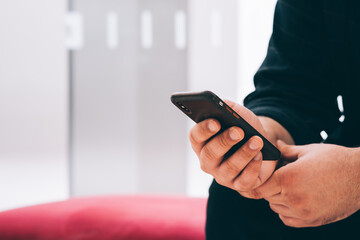 Cropped view of man holding digital smartphone chatting online in social networks and updating application on smartphone device using 4G internet connection.Copy space area for mobile advertisement