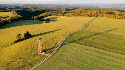 Yellow metal lookout tower in the middle of the fields in hilly landscape, aerial photo, Czech Republic