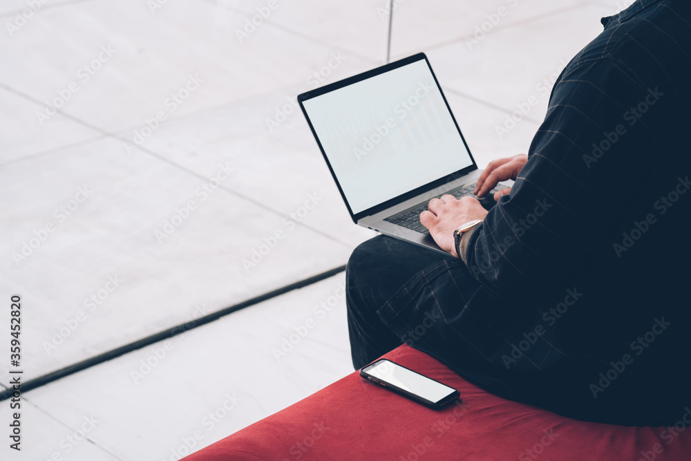 Poster cropped view of man's hand typing text on keyboard of modern laptop computer with blank screen area 