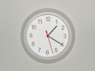 eine Wanduhr auf grauem Hintergrund zeigt die Zeit 01:20 Uhr