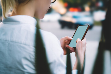 Cropped view of young woman holding modern smartphone device with blank screen area for internet website and chatting in social networks.Hipster female blogger typing text message on cellular
