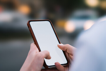 Cropped view of woman's hands holding smartphone with blank screen area for your internet content on website.Selective focus on female fingers typing text message on telephone with mock up area