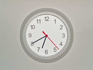 eine Wanduhr auf grauem Hintergrund zeigt die Zeit 06:40 Uhr