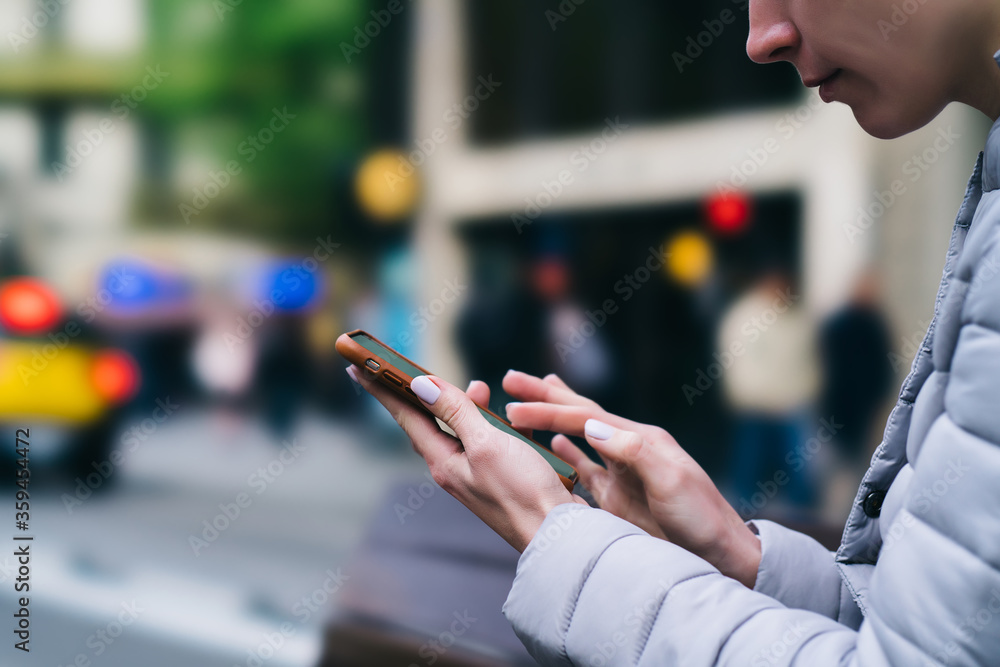 Aufkleber cropped side view of young woman holding smartphone device and typing with fingers on device using 4