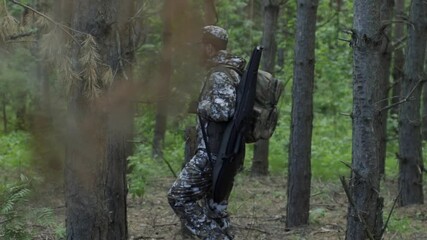 Two hunter men in camouflage clothes with guns walking through forest during hunting season. Man hunter outdoor in forest hunting. Male Tourists. Slow motion - Powered by Adobe
