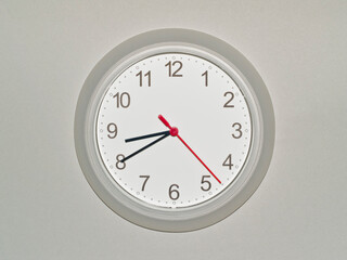 eine Wanduhr auf grauem Hintergrund zeigt die Zeit 08:40 Uhr