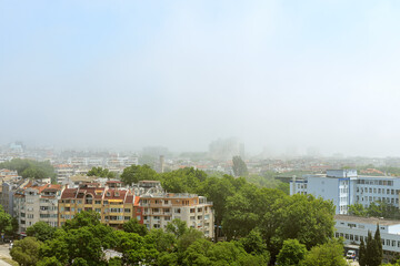 Dense fog on a sunny summer day in Varna. Thick fog came from the sea and covered the city. Climate and weather changes.