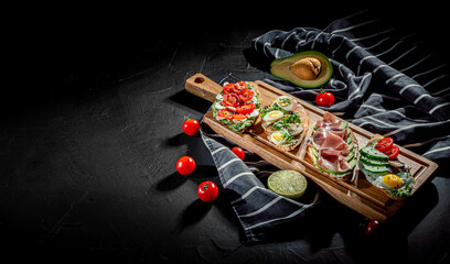 Obraz na płótnie Canvas Traditional italian bruschetta on toasted slices of baguette seasoned with spice and herbs and garnished with fresh basil on a wooden board