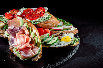 Traditional italian bruschetta on toasted slices of baguette seasoned with spice and herbs and garnished with fresh basil on a dark background