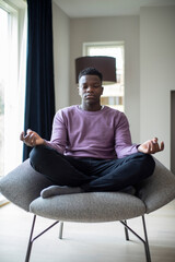 Peaceful Teenage Boy Meditating Sitting In Chair At Home