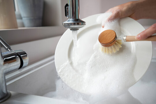 Woman Washing Up At Home Using Eco Dish Brush For Sustainable Lifestyle