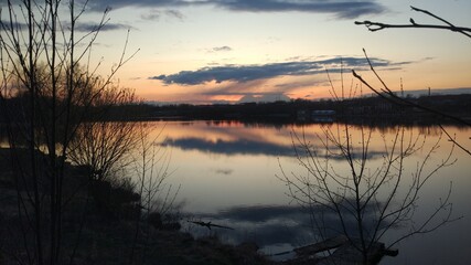 Spring sunset with reflection sky clouds on the river