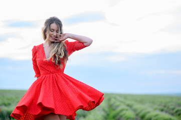 Happy woman in red dress dancing and jumping in lavender field
