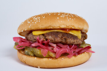 Juicy burger with cucumbers, lettuce, cheese on a white background