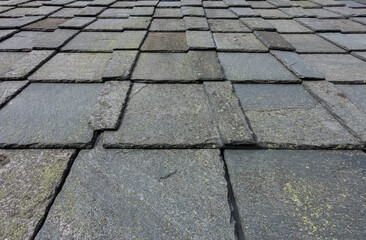 Old roof slate tiles roof with blue sky and clouds.