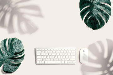 Computer keyboard with tropical leaves and shadow - flat lay