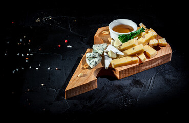 Various kind of cheese served on wooden table, traditional pieces of french and italy cheese on dark background
