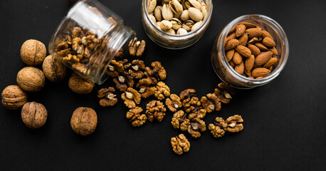 Walnut scattered on the black table from a jar. Walnut is a healthy vegetarian protein nutritious food.