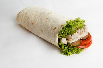 Hot roll with chicken, lettuce, cucumber and tomatoes. Close-up