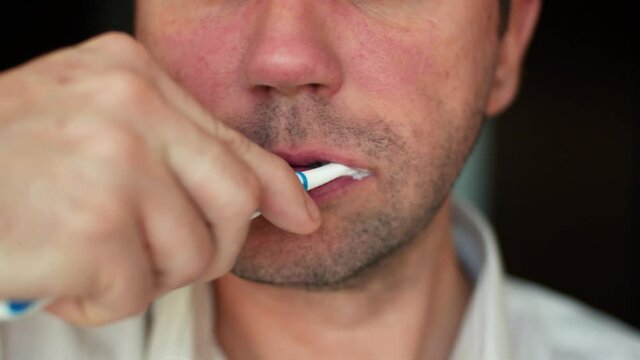 Human oral hygiene. Unshaven caucasian man is brushing his teeth close-up 