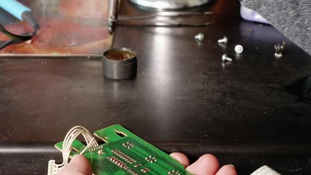 Close up of man's hands soldering microswitch electrical card using slodering iron.