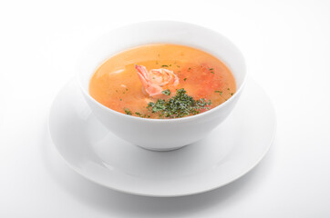 soup with shrimp and tomatoes in a white tureen on a white background. Served with greens