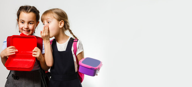 Two Young Girls Whispering And Sharing A Secret During Class In School