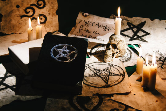 Occult grimoire, magic book laying on table with occult symbols, candles, pentagrams, fortune telling, ritual, altar, spiritism, secret knowledge, scull