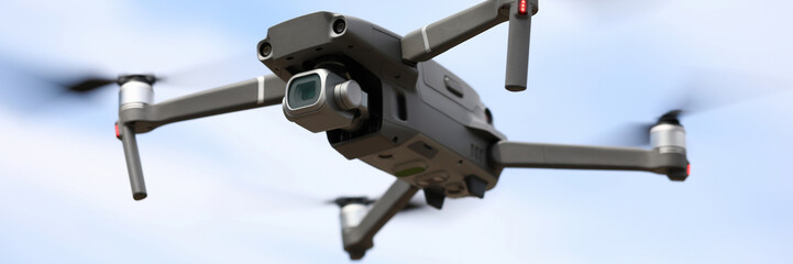 Close-up of digital camera on drone with remote control. Modern copter flying in sky. Shooting propeller option. Technology and innovation concept