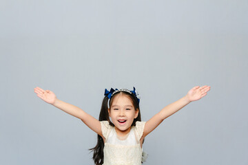 Portrait of a laughing cute 6 years old Asian girl with her arms rised up in happines