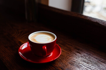 Hot coffee with latte art in a white cup with saucers on a wooden table. Cappuccino with foam. Cup of coffee on a wooden table. Top view. Place for text. Cappuccino with latte.