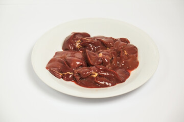 Raw chicken liver in a white plate on a white background