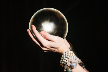 Naklejka premium Fortuneteller's hands on a glass orb on black background. Prediction of the future