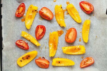 Slices of yellow bell pepper and red tomato prepared for baking with spices, top view