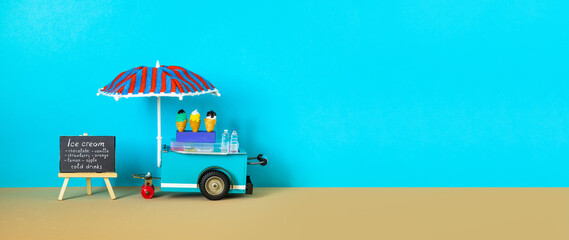 Ice cream toy cart with blue red umbrella. Assortment of ice cream menu black chalkboard. Summer...