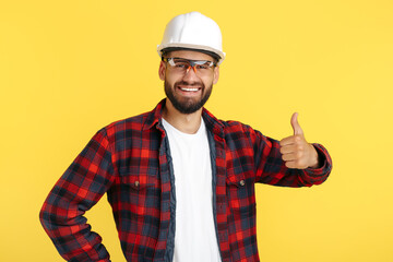 Handsome bearded engineer or constructor man in casual outfit show good gesture over yellow background. - obrazy, fototapety, plakaty