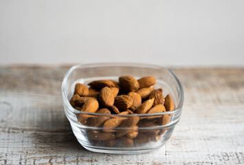 Almonds in a small plate on a vintage wooden table. Almond is a healthy vegetarian protein...