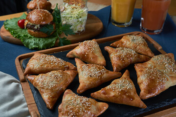 Uzbek dish - mini samosa with sesame seeds on a stone slab. Light effects