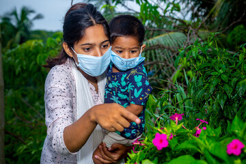 Little boy and mom wearing medical mask. A little boy and mom are traveling in the garden. Protect from the coronavirus infection on home quarantine.