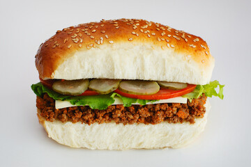 Juicy sandwich with cucumbers, lettuce, cheese and chopped meat on a white background