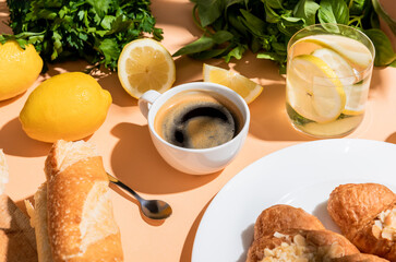 coffee, fresh croissants and water for breakfast on beige table