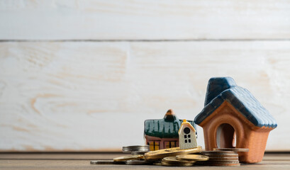miniature house model with coins on wood background
