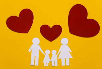 Paper happy family together with red hearts on yellow background