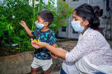 Little boy and mom wearing medical mask. A little boy and mom are traveling in the garden. Protect from the coronavirus infection on home quarantine.