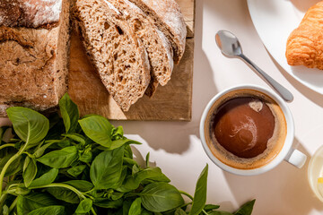 top view of bread, basil and cup of coffee for breakfast on grey table
