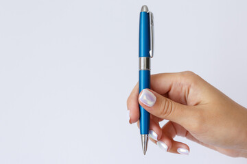 Gesture and sign, female hand holding a metal blue pen on a white background. Empty space for text