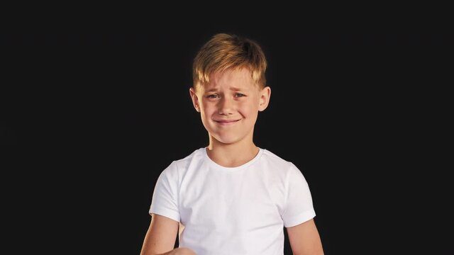 Refusal sign. Stop rejection. Confused boy smiling showing no gesture isolated on black background.