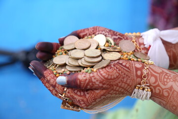 Girl's hand in golden coin in  Indian traditional wear Hindu culture wedding celebration 