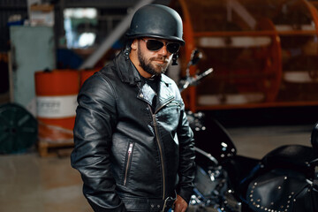 Portrait of bearded man motocyclist in dark sunglasses on dark background